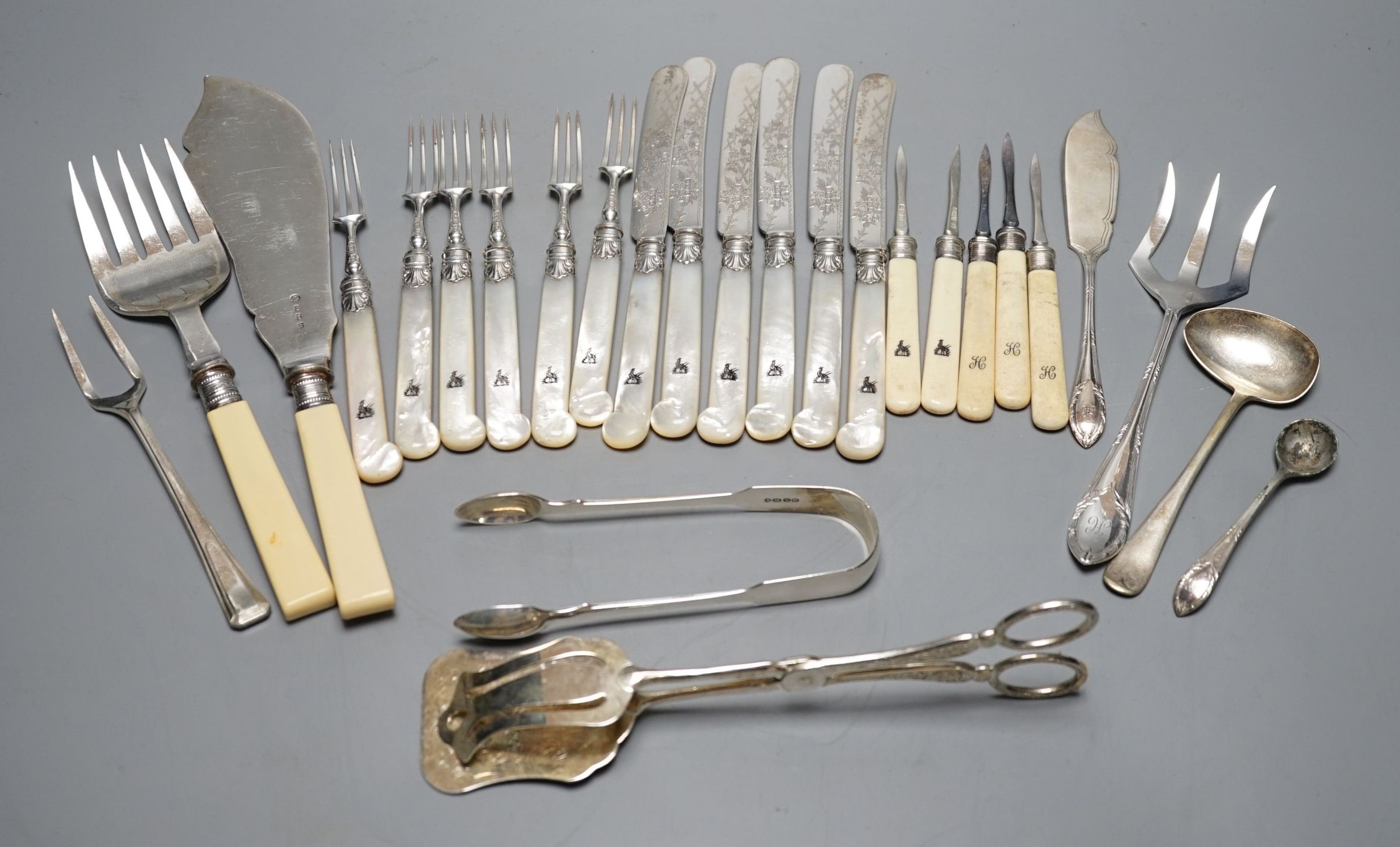 Six pairs of George V mother of pearl handled silver dessert eaters, George Howson, Sheffield, 1921, a pair of silver sugar tongs and assorted plated flatware.
